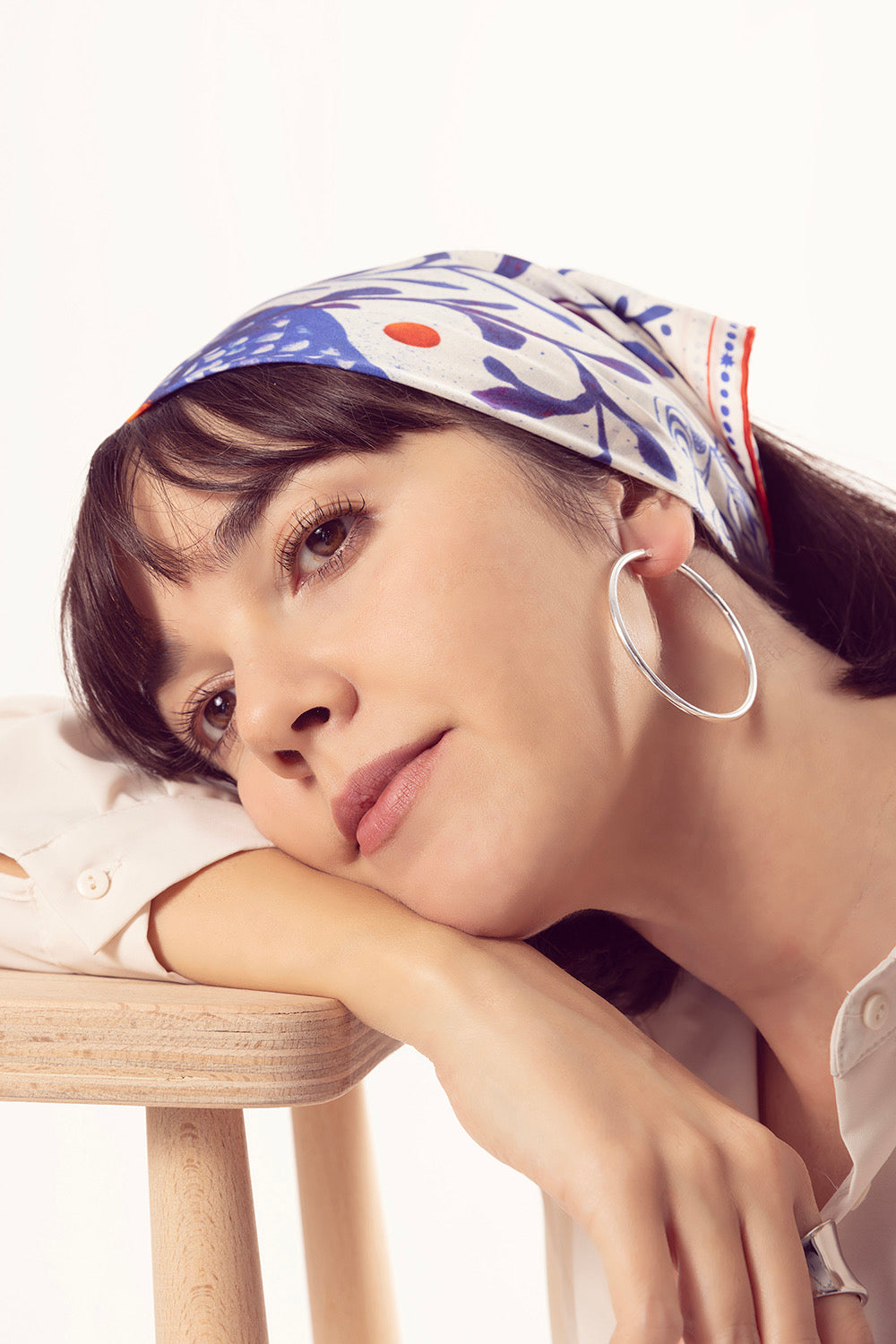Woman wearing a patterned silk scarf as a stylish bandana headpiece.