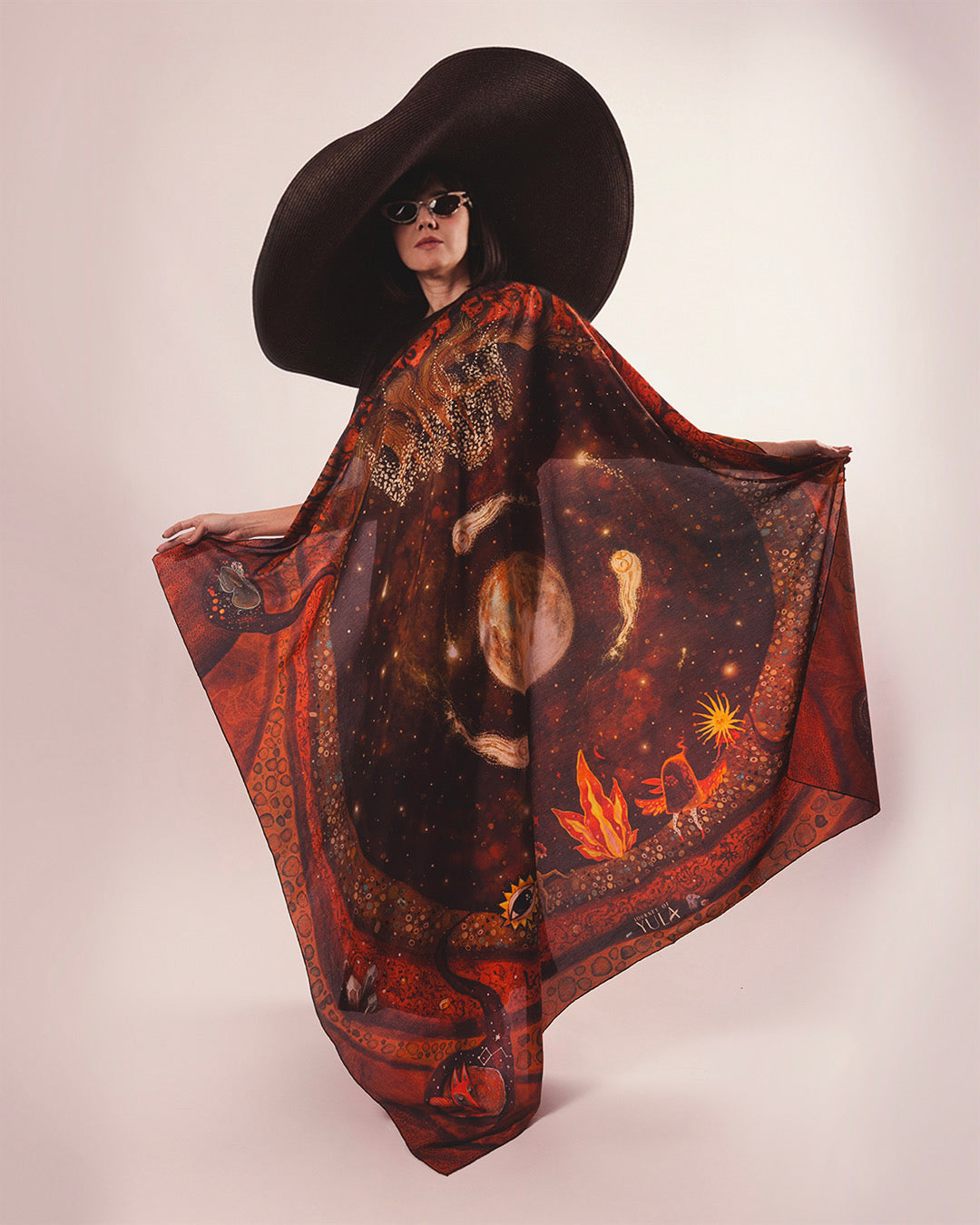Full-view showcase of hand-illustrated celestial silk scarf worn as a statement cape by a model against white background.
