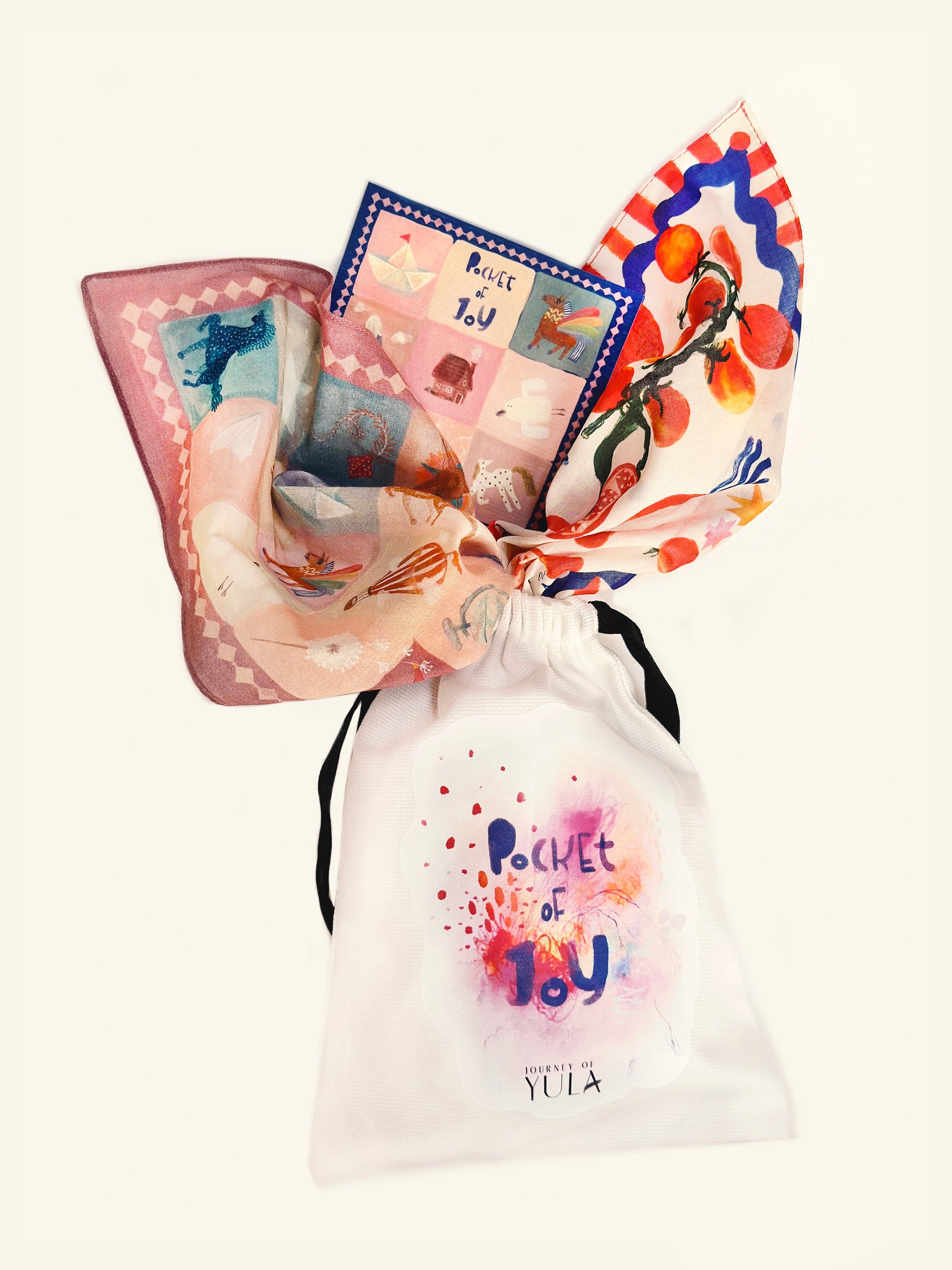 Journey of Yula cotton scarf set featuring a vibrantly illustrated scarf and a signature 'Pocket of Joy' cotton gift bag on a clean white background.