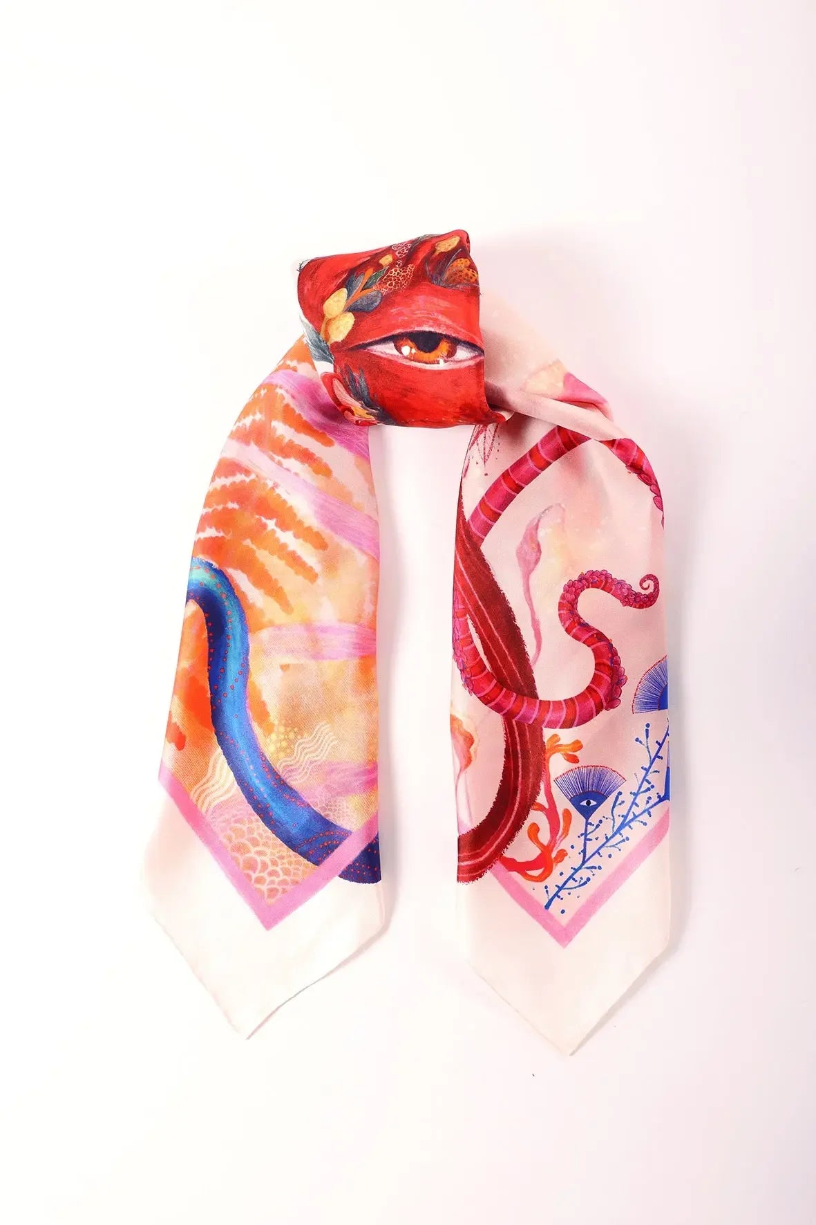 Kirmizi tonlarda desenli kare ipek fularin katlanmis urun fotografi goz detayı