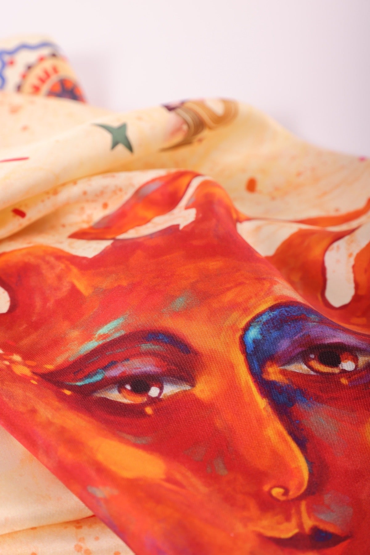Close-up highlighting the expressive eyes of the sun character illustrated on a fine silk scarf.