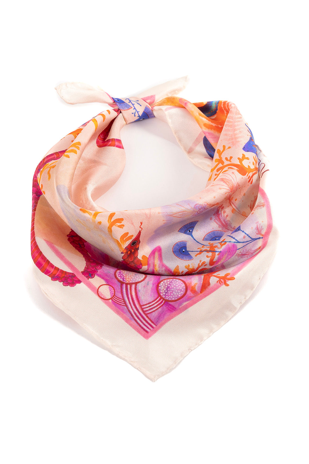 The "Heart Aflame" silk scarf tied in a classic neck knot, highlighting the soft pink and coral tones of the silk fabric.