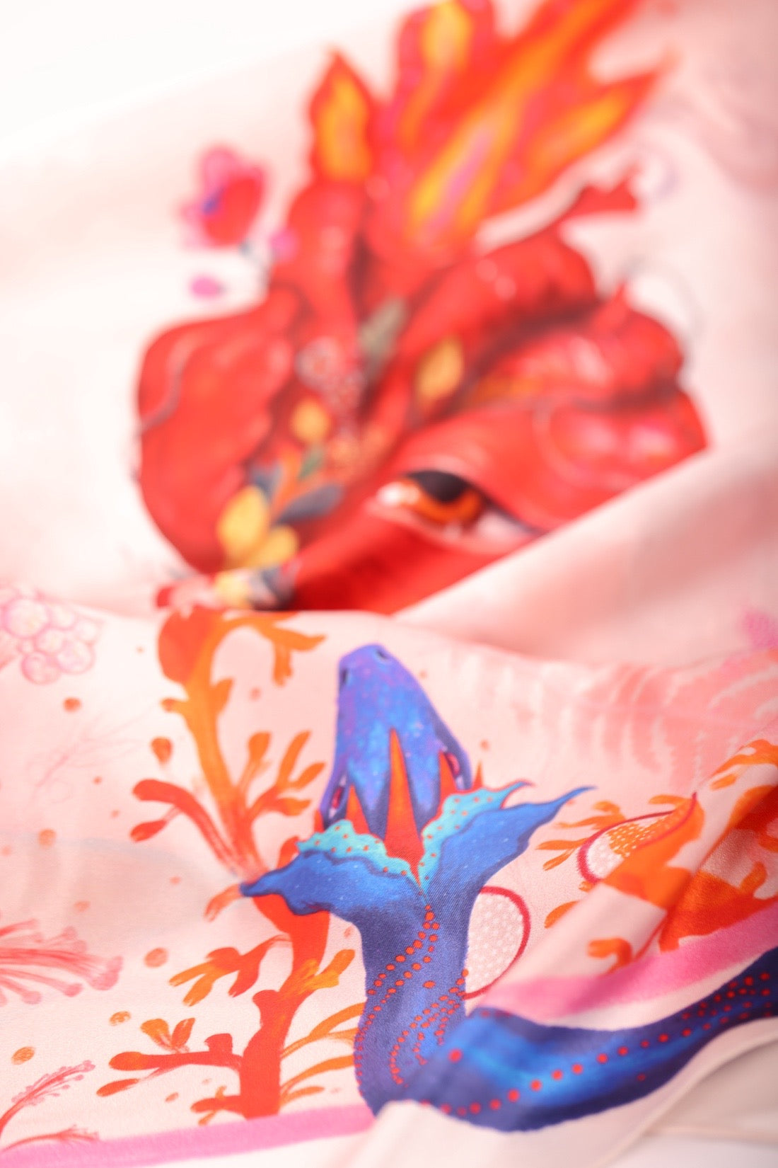 Macro shot of the anatomical flaming heart and blue snake illustrations on a luxury silk accessory.