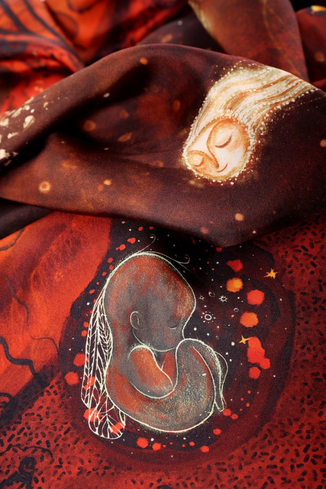 Close-up detail of a silk scarf design featuring a cosmic baby and celestial nebula illustration.