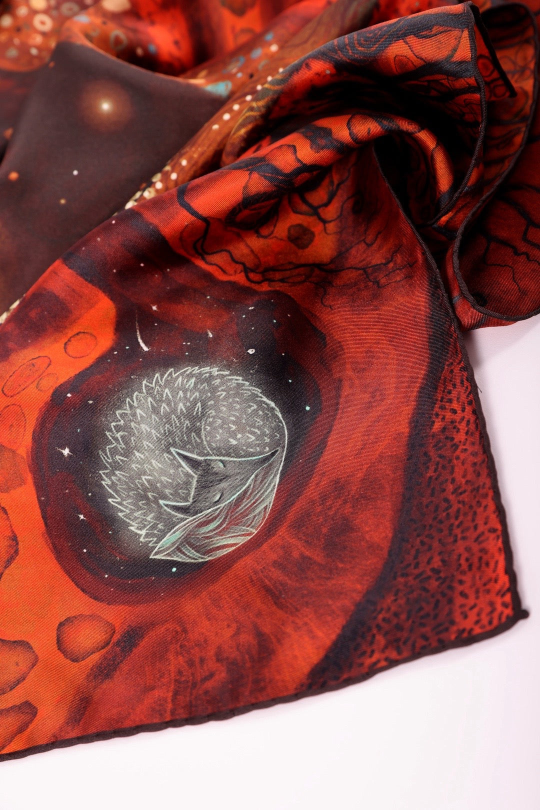 High-quality silk scarf detail showing a hand-drawn sleeping hedgehog in a starry night sky.