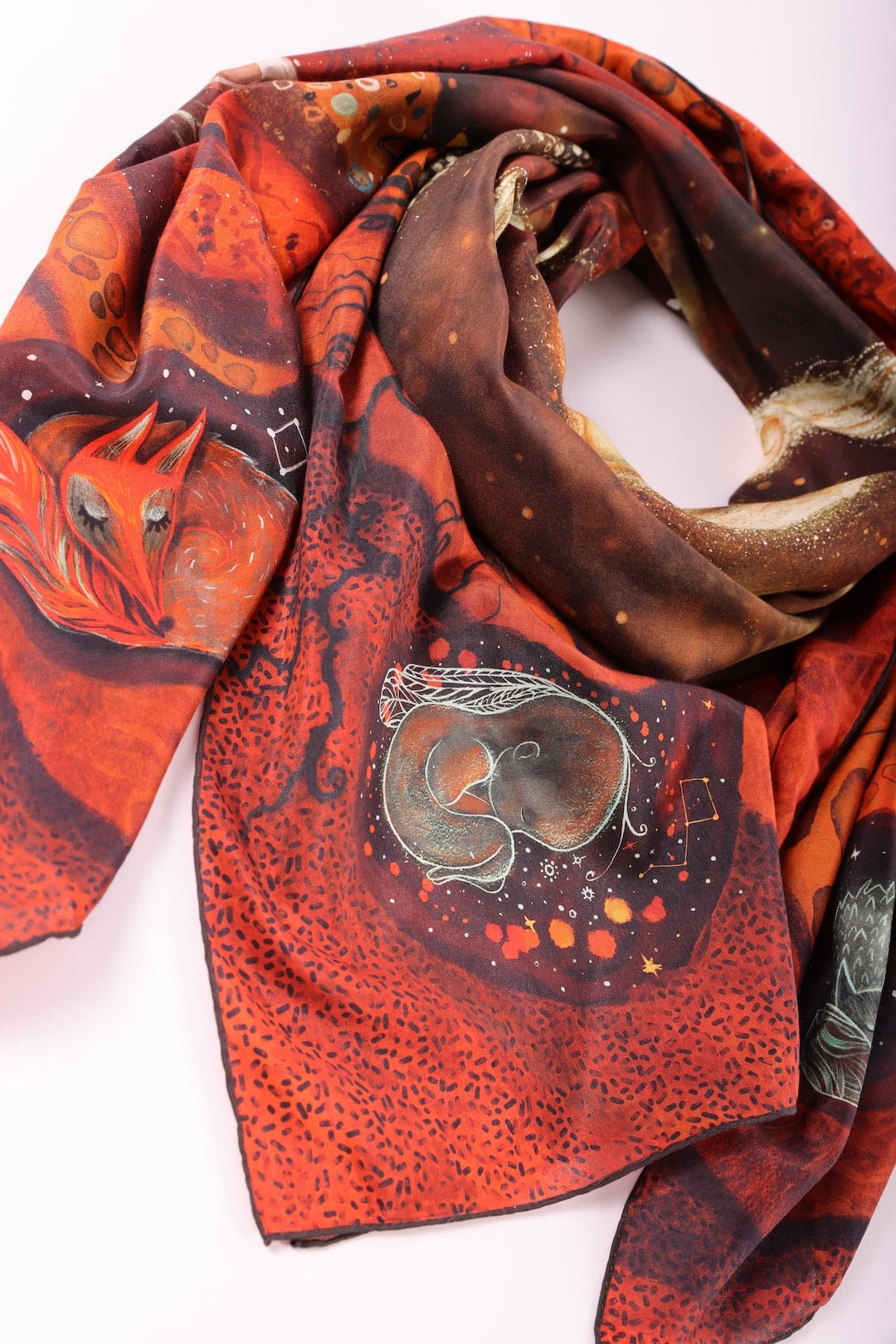 Detailed close-up of a folded silk scarf emphasizing the symbolic embryo and roots illustration representing birth and connection.