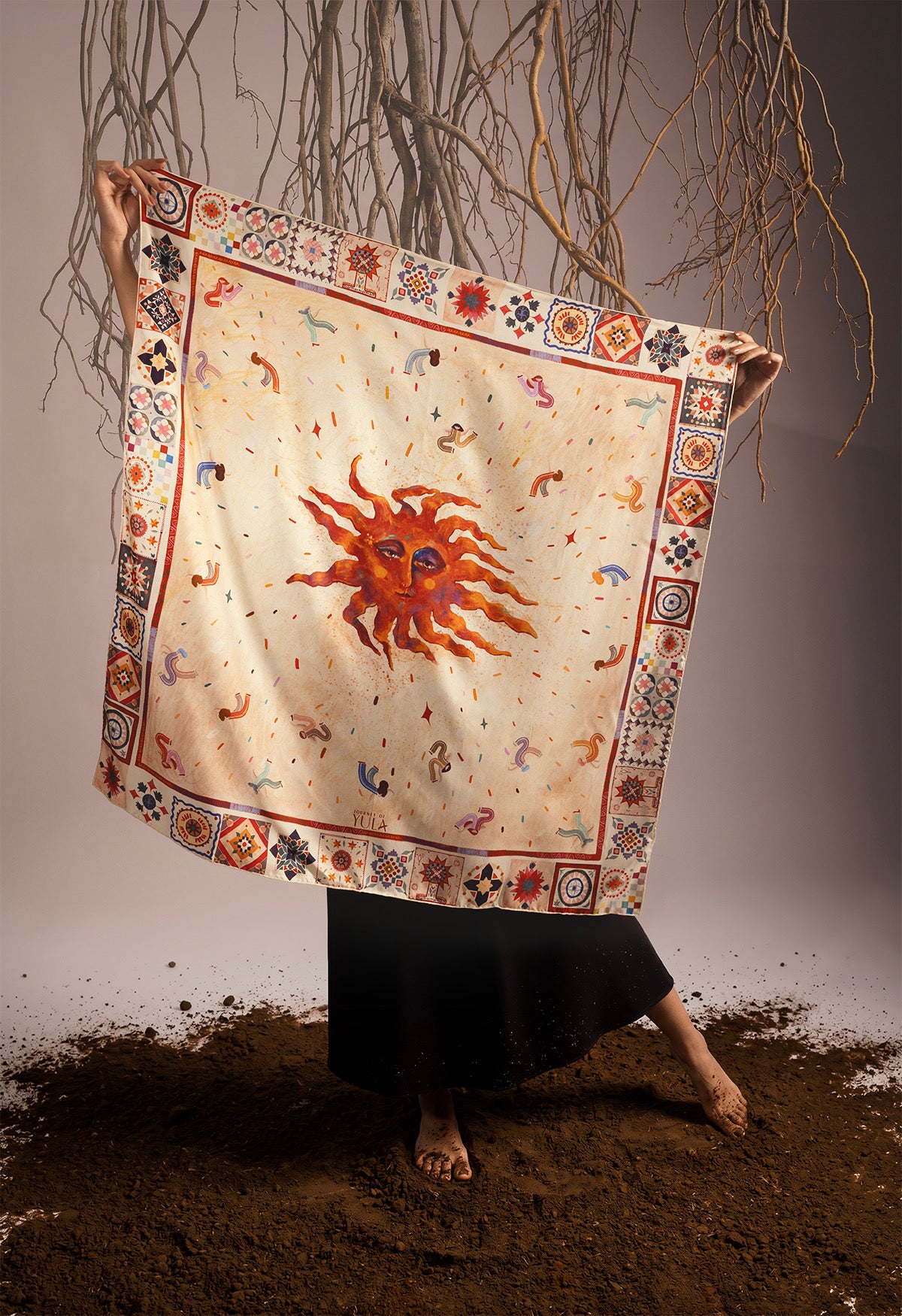 Full view of a square silk scarf by Journey of Yula featuring a central artistic sun illustration and intricate geometric borders.