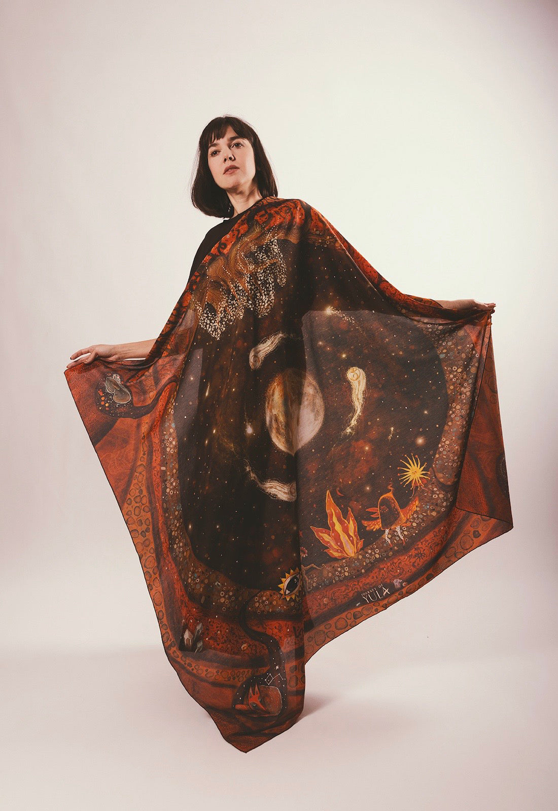 Full-view showcase of hand-illustrated celestial silk scarf worn as a statement cape by a model against white background.