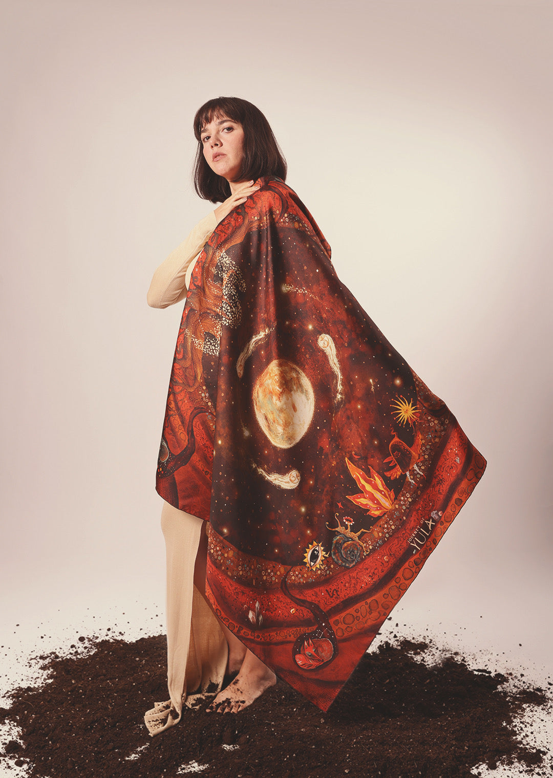 Side view of a model showcasing the flow and drape of a red and orange silk scarf with mystical patterns.