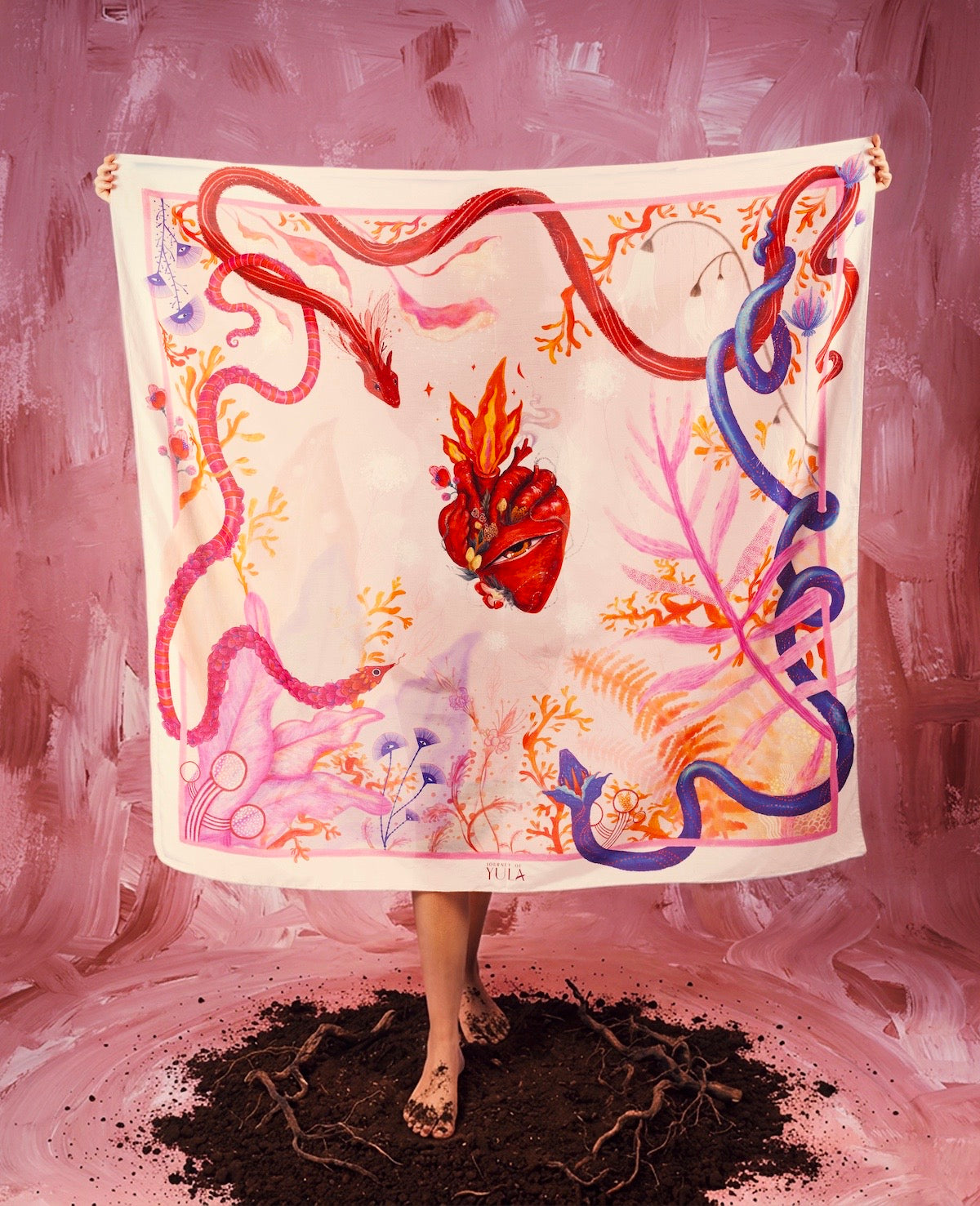 Full display of a large square silk scarf by Journey of Yula with a central flaming heart motif, whimsical snakes, and pink coral patterns.