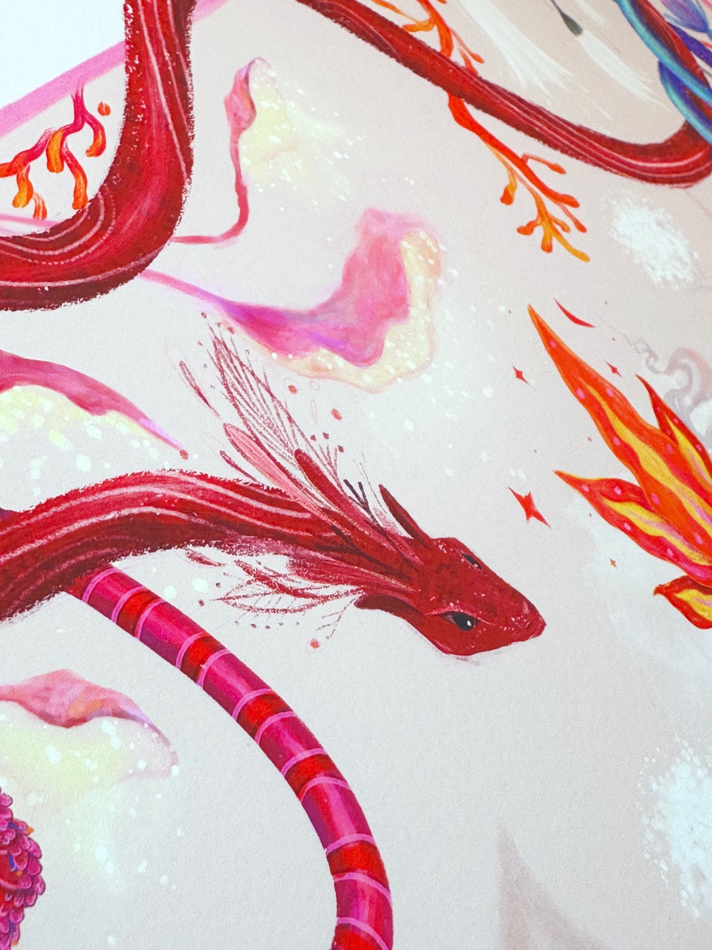 Close-up detail of "Heart Aflame" art print showing a mystical red winged serpent and delicate pastel botanical illustrations on high-quality paper.