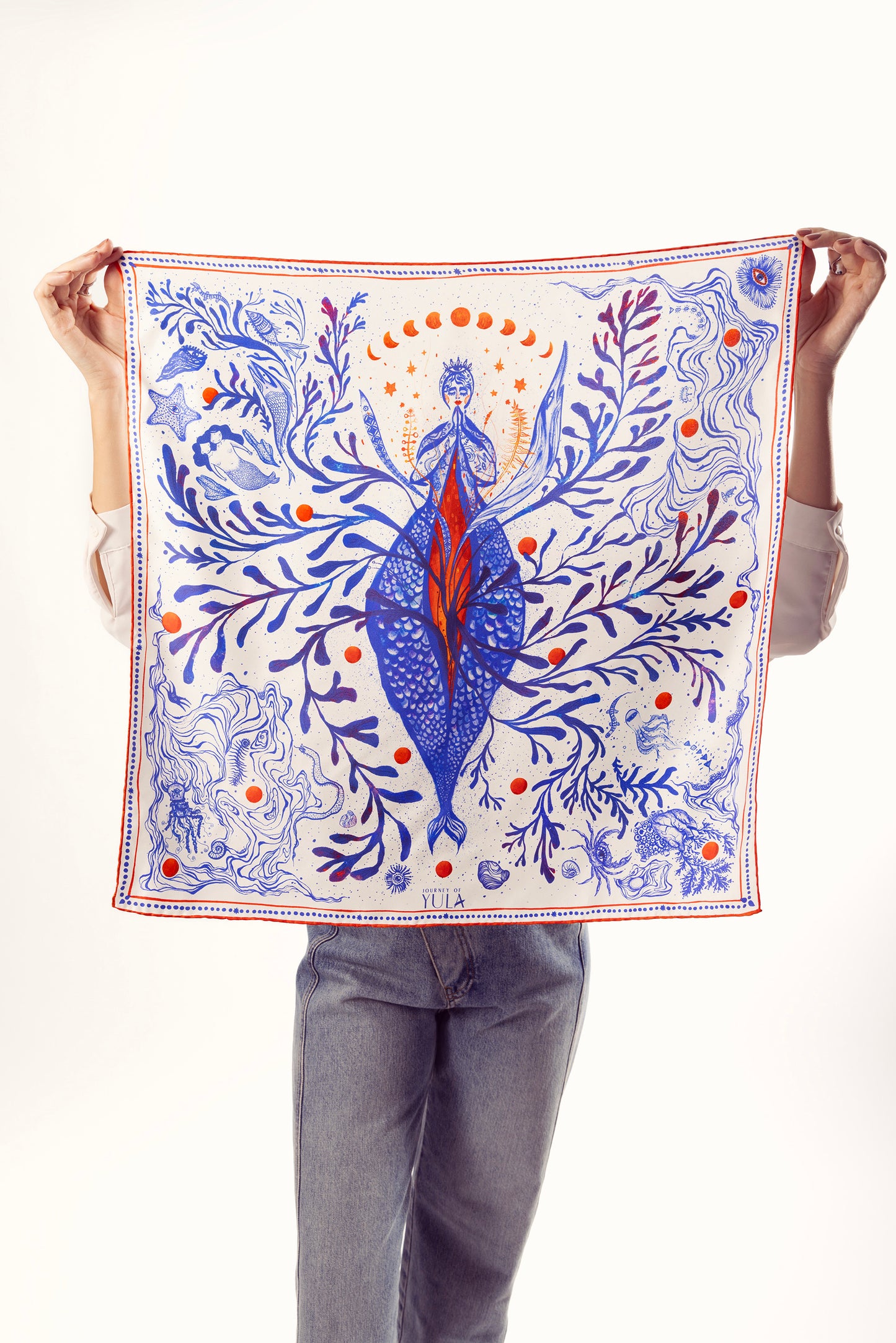 Woman holding square illustrated silk scarf with blue and red artwork