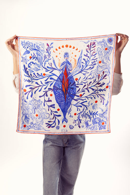 Woman holding square illustrated silk scarf with blue and red artwork