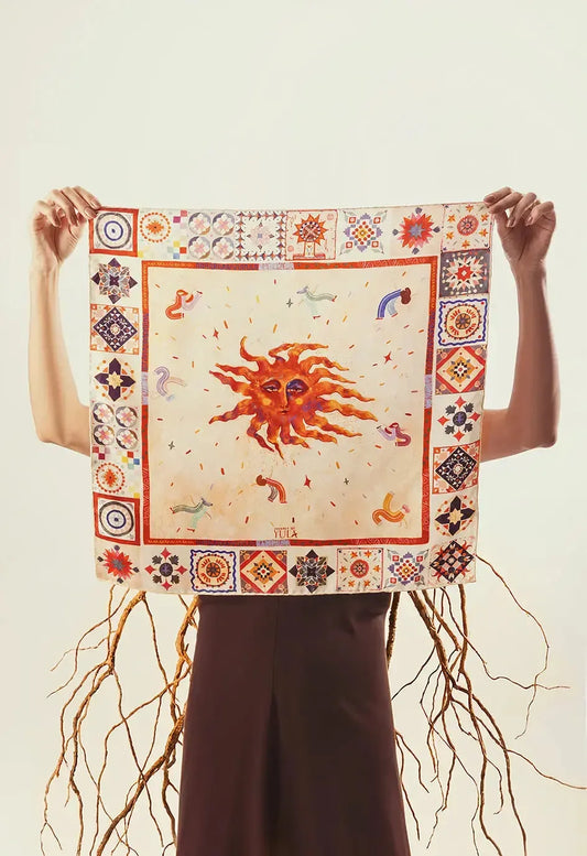 Journey of Yula Natus et Radix serisi turuncu gunes ve etnik desenli yuzde 100 saf ipek fular elde tutan model