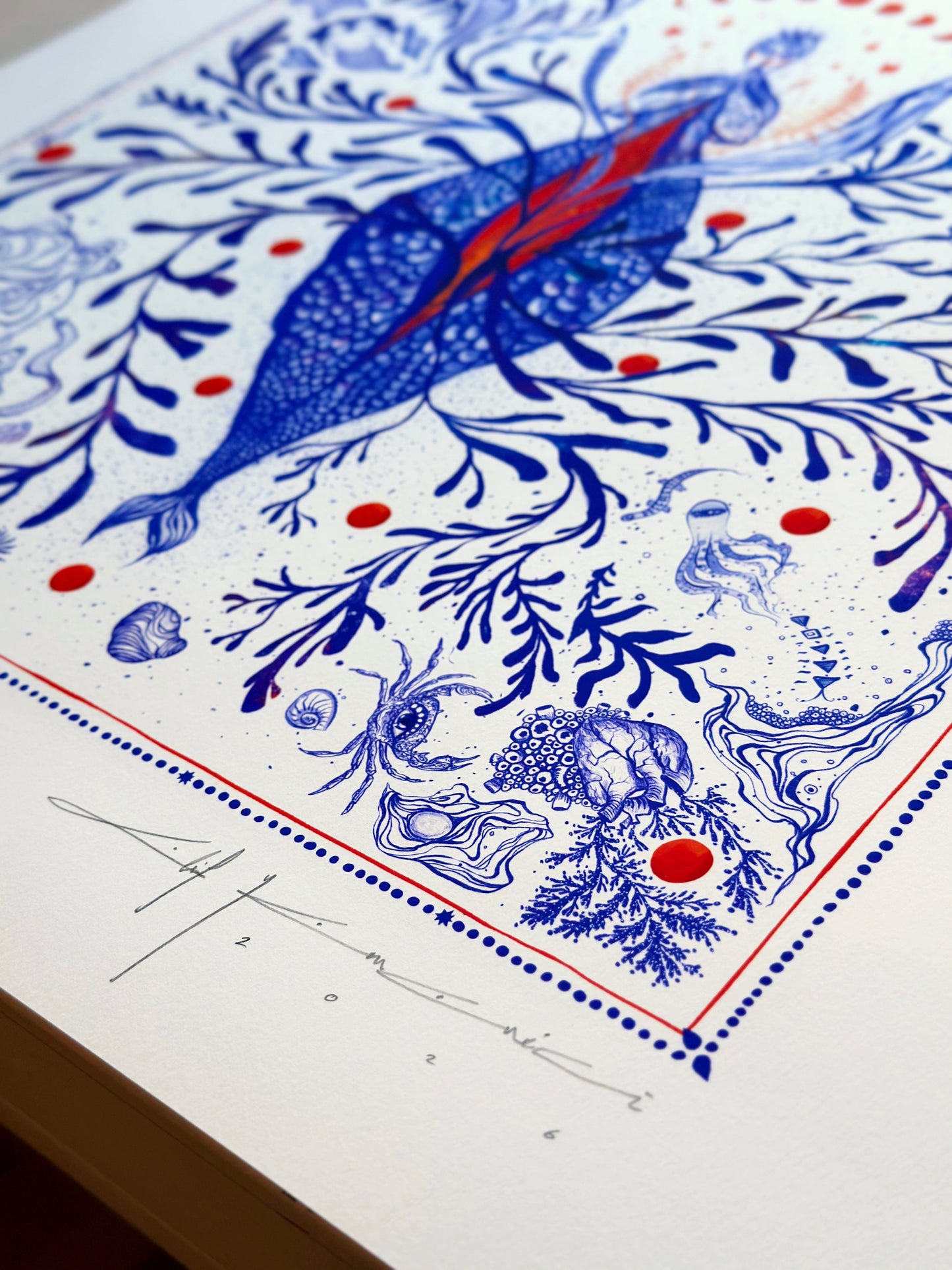 Detailed view of the artist's signature on a marine-themed illustration, showing sea shells, octopus motifs, and delicate blue line work.